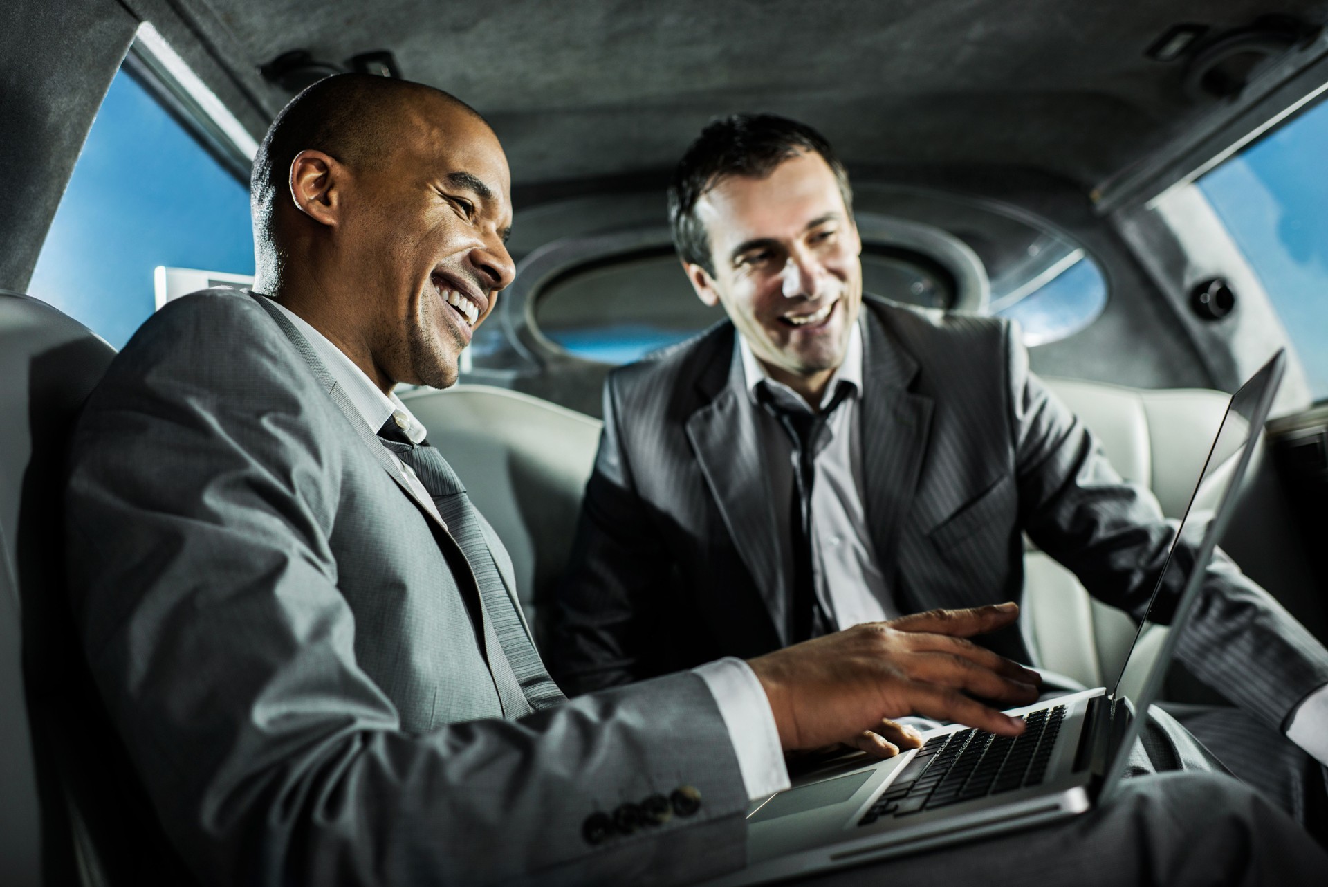 Businessmen using laptop in a limousine.